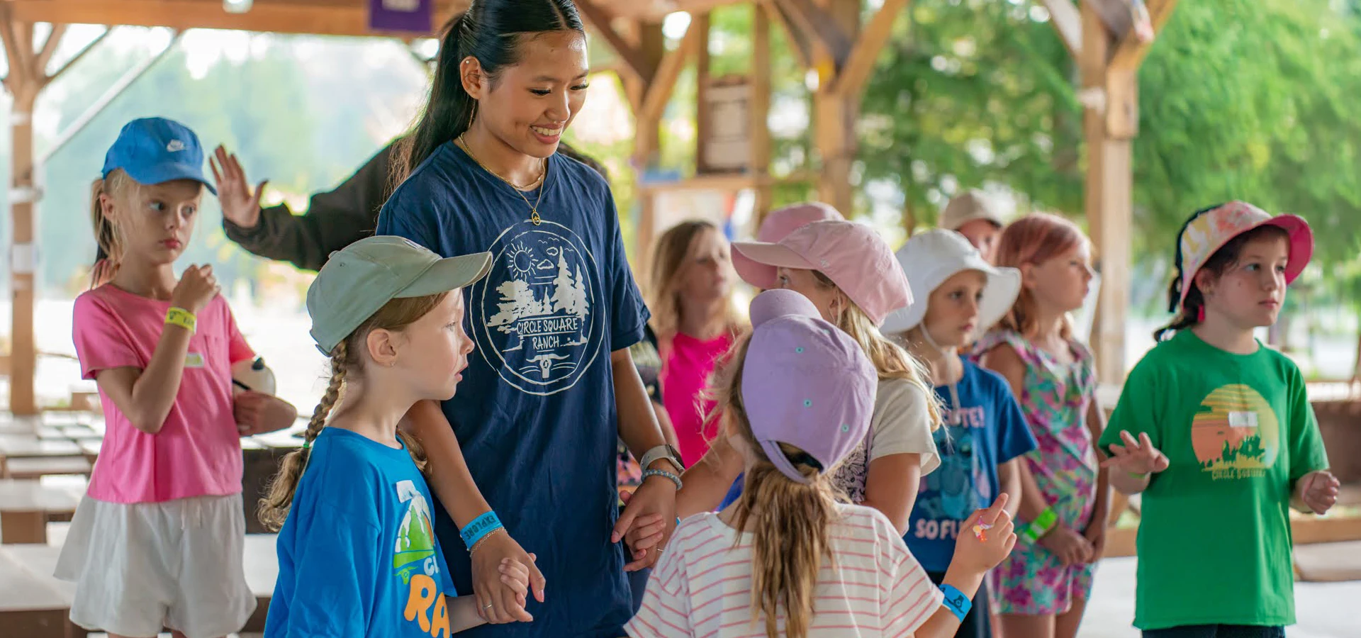 Children wearing colorful hats and casual clothes stand outdoors, engaging in a group activity.